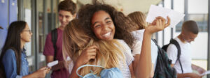 Two young students hugging after receiving an acceptance letter.