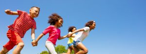 A diverse group of children running while holding hands.