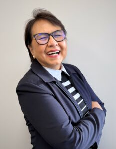 A photo of Arnida, smiling with her arms crossed.