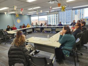 People sit at tables in the CBFY office while learning about Canadian Law.